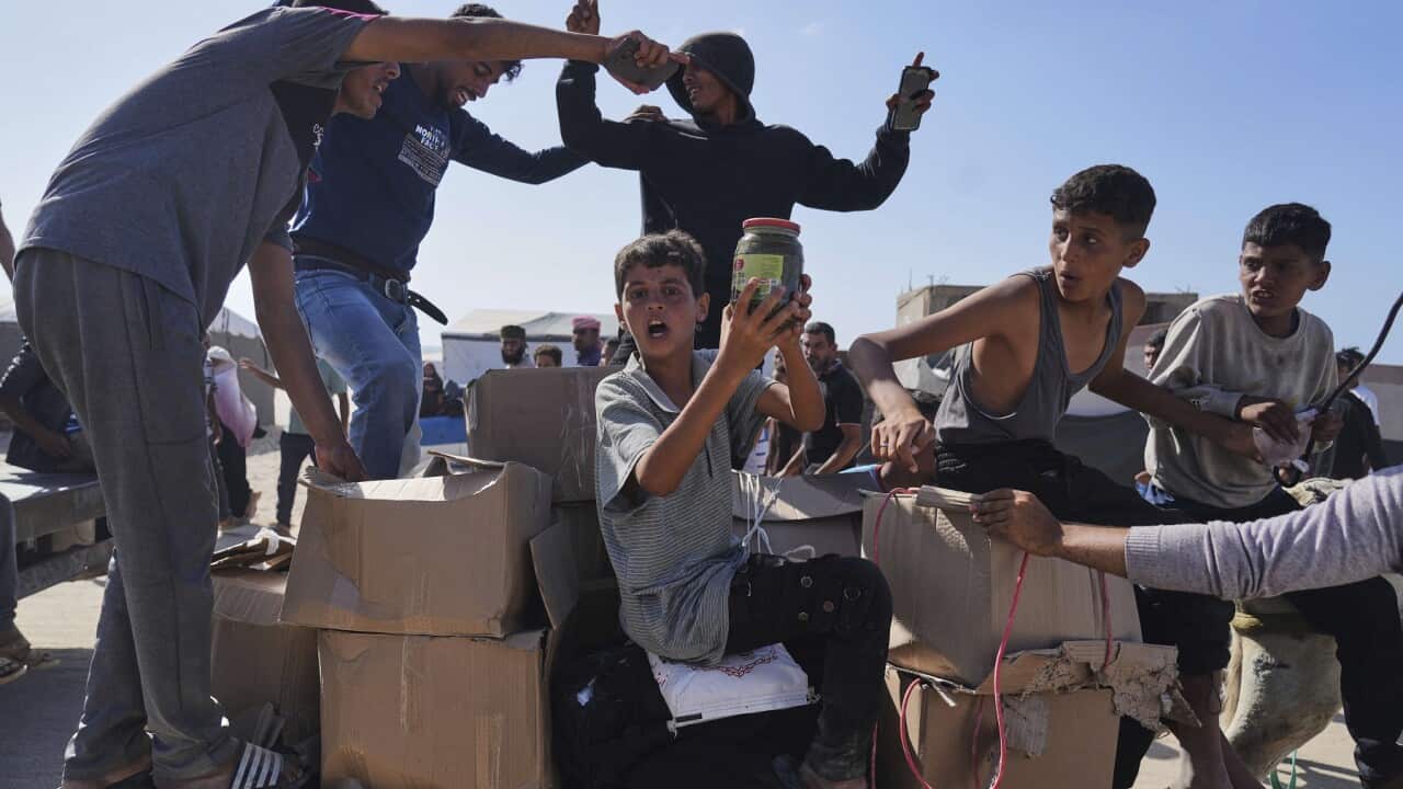 Palestinians carry boxes containing food and humanitarian aid packages delivered by the Gaza Humanitarian Foundation.