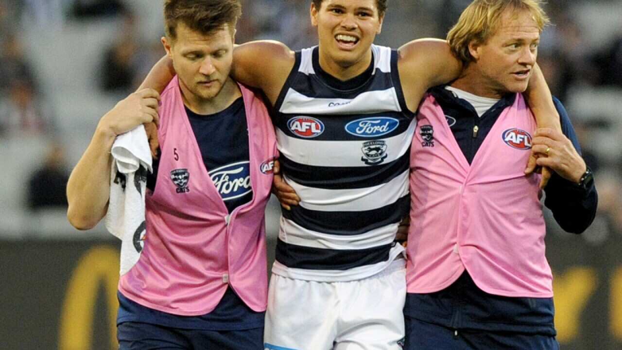 Brandan Parfitt of the Cats is assisted off the ground