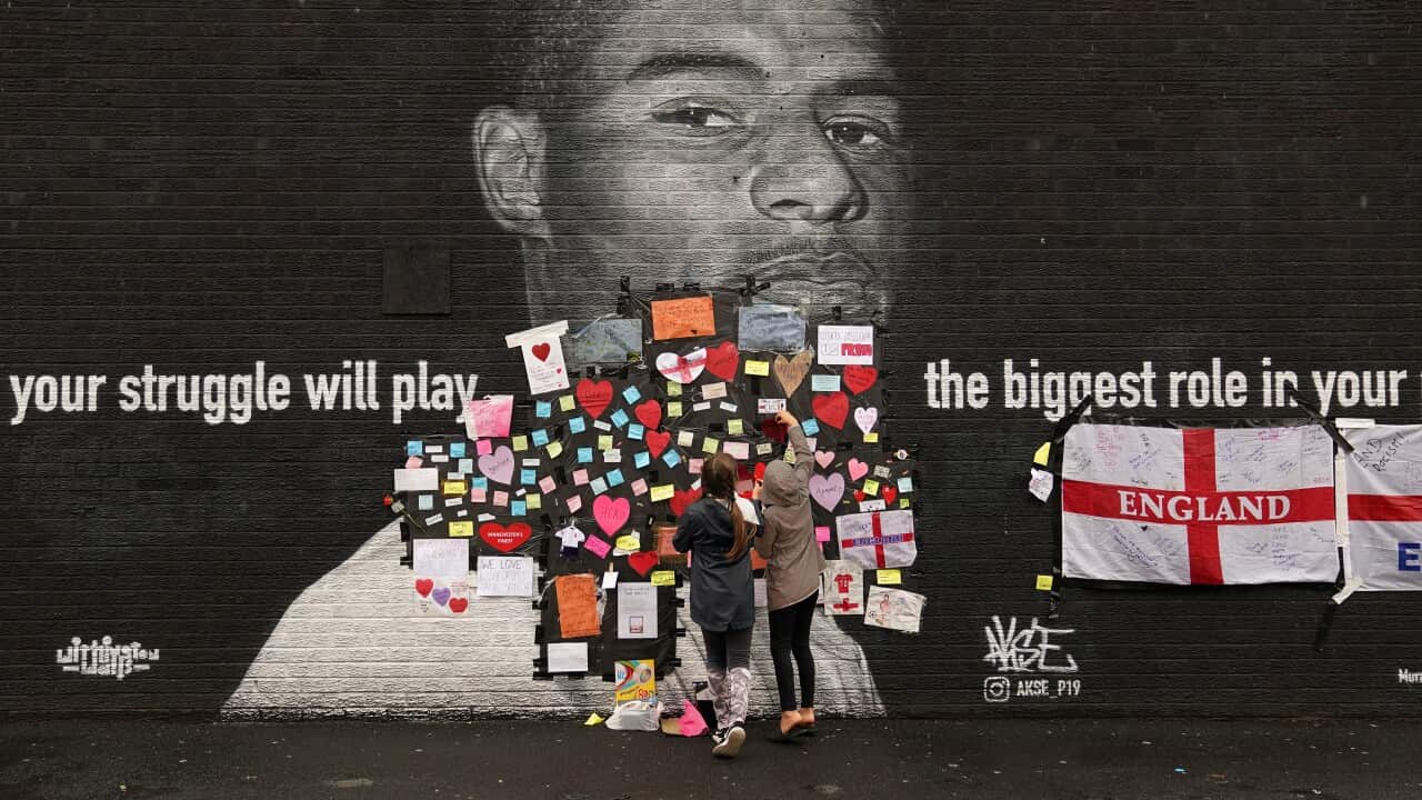 Fans place messages of support on top of bin liners taped over offensive wording on the mural of Manchester United striker and England player Marcus Rashford.
