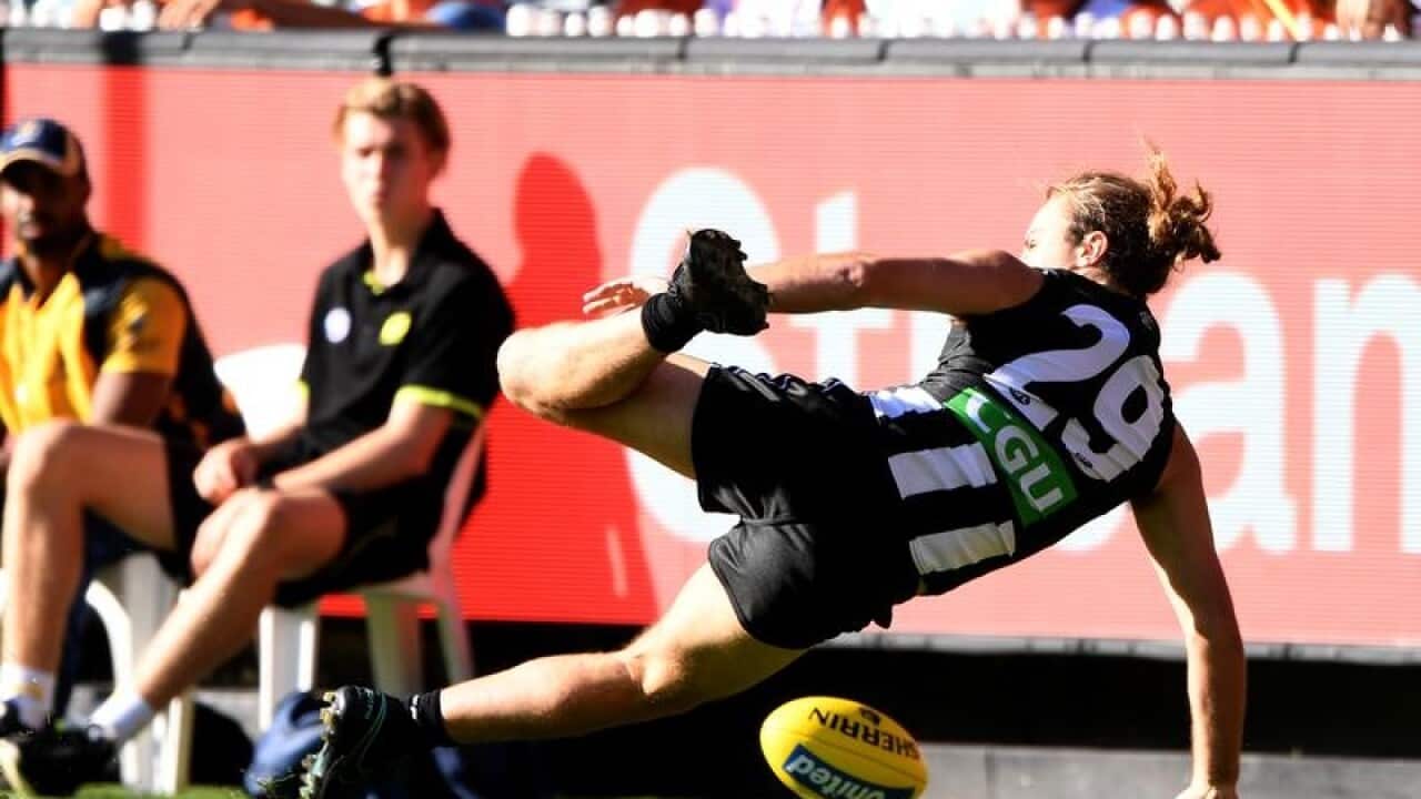 Collingwood's Tim Broomhead falls after crashing into the goal post