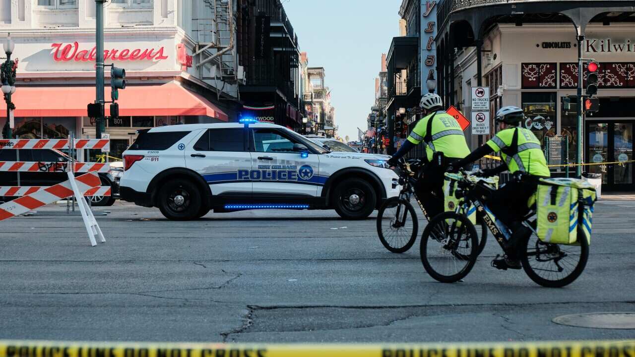 A police car and two people in his vis on bikes in an area marked off by police tape.