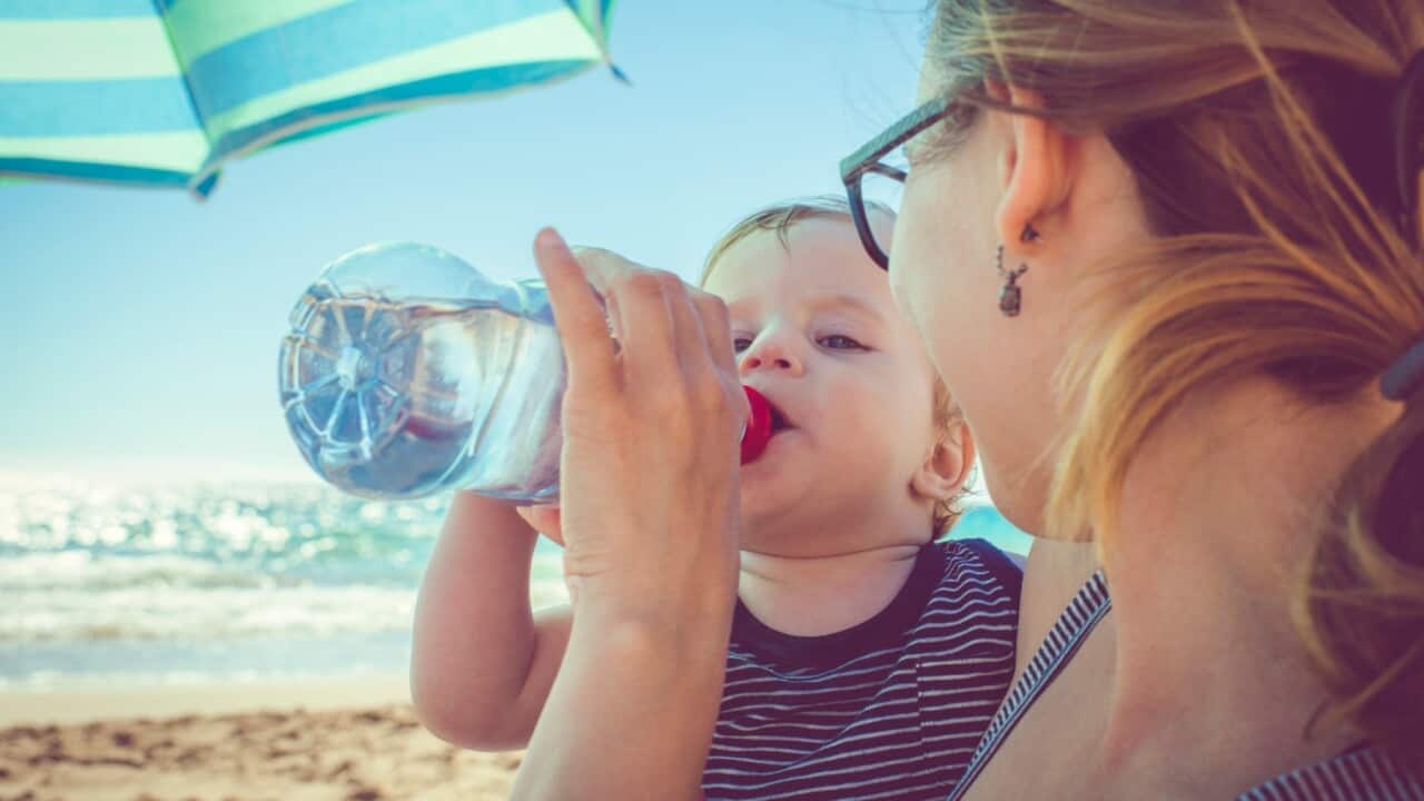 Baby drinking water on beach Getty Images.ArtMarie