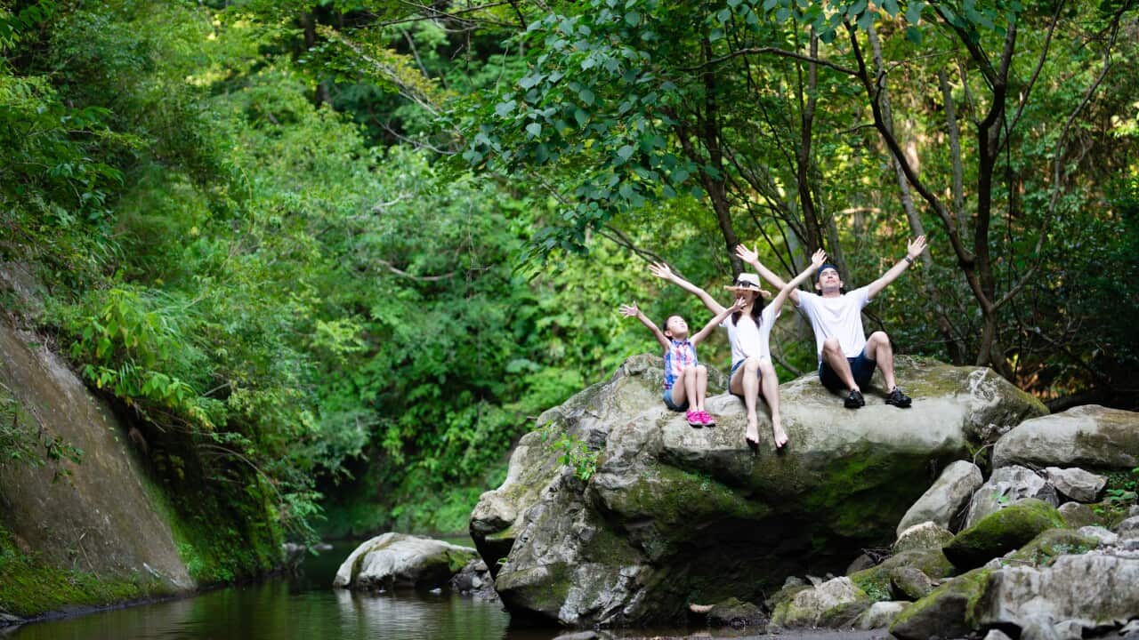 Father, mother and daughter playing in the mountain stream