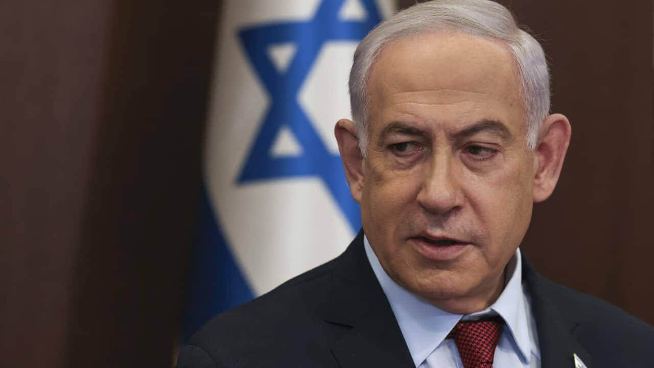 A man wearing a suit and tie standing in front of an Israeli flag.