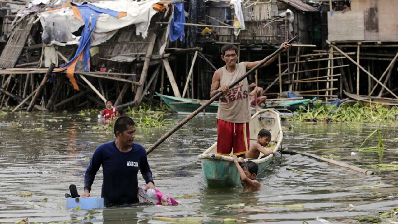 Filipino fishermen with a backdrop of damaged houses, Philippines,
