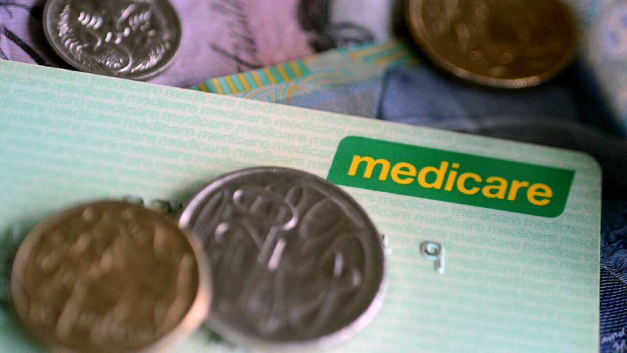 Bank notes and coins are seen with a Medicare Card in Brisbane