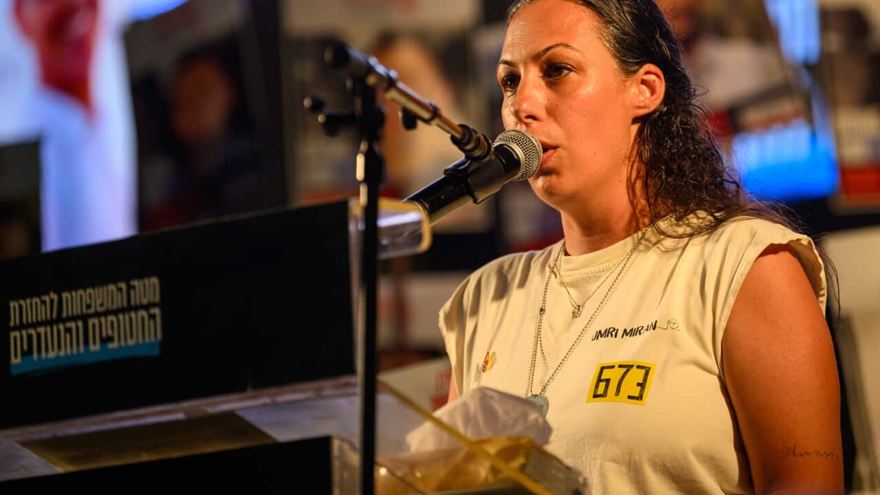 A woman in a white t-shirt speaking into a microphone