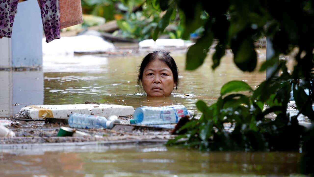 A woman wades through a submerged street at the UNESCO heritage ancient town of Hoi An after typhoon Damrey hits Vietnam