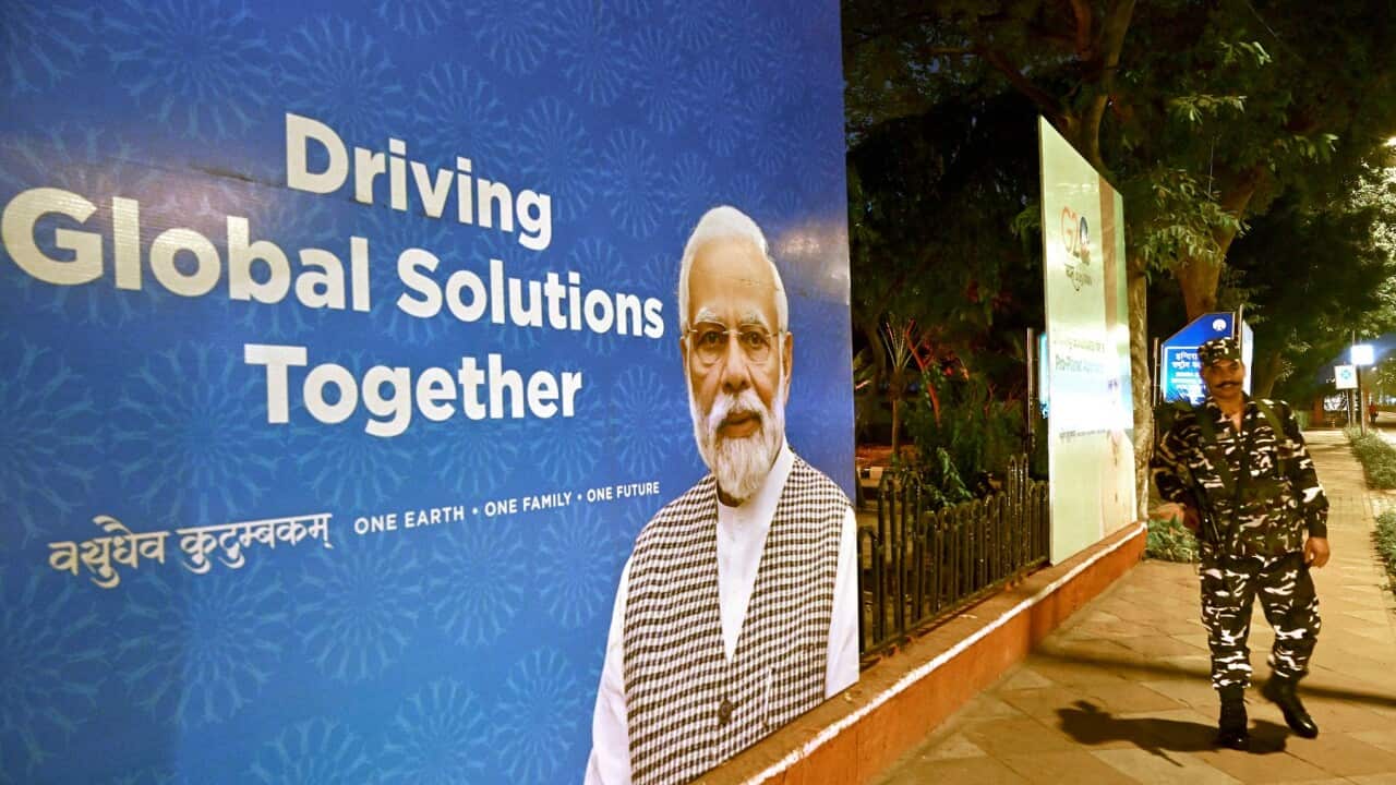 Indian security personnel stands guard next to a G20 communication billboard (Getty)