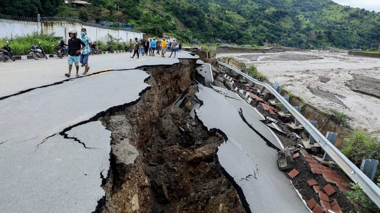 Officials inspect a damaged road in the aftermath of floods in Dili, Timor Leste