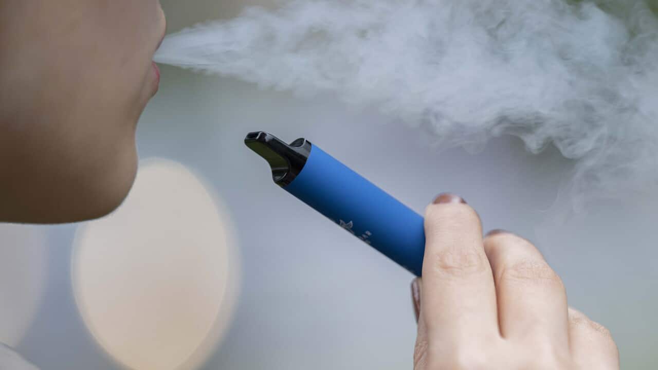 A close up image of a person vaping out of a blue vape