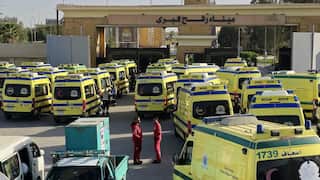 Rows of ambulances queue outside a brick border crossing structure.