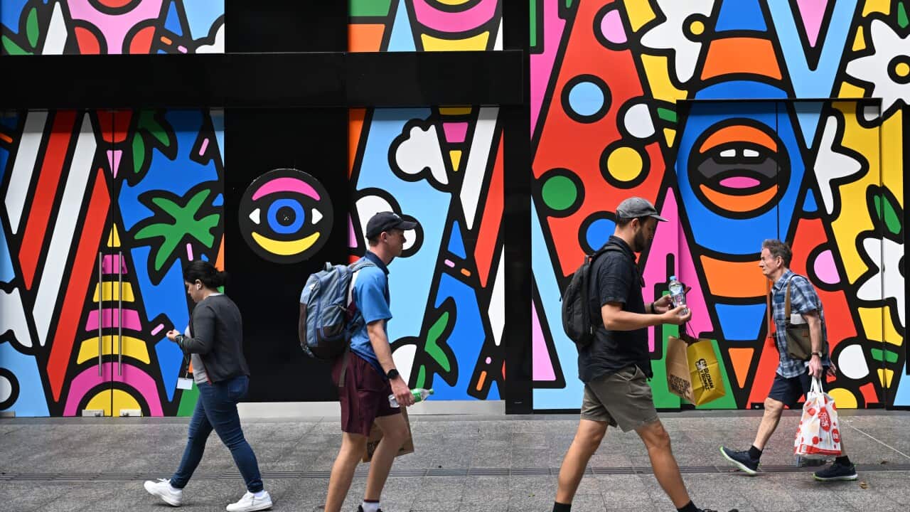 Four people walking past a mural in Brisbane.