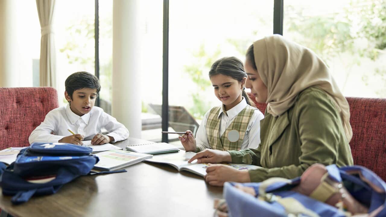 Saudi school children doing homework with their mother