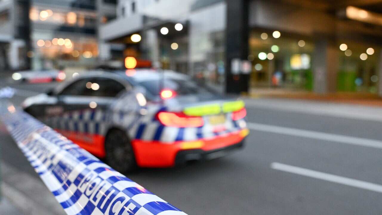A police car behind blue and white chequered police tape.