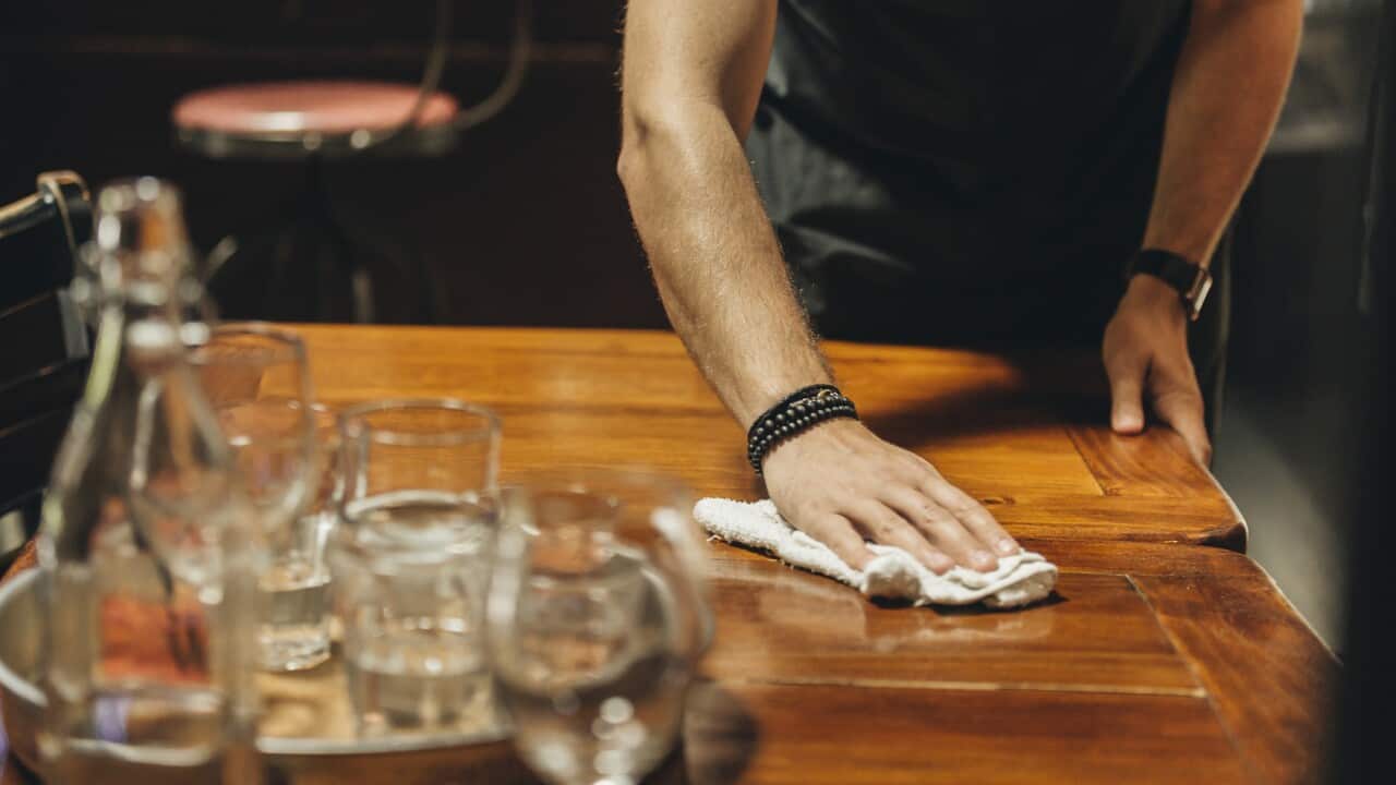 Midsection of waiter cleaning table in bar