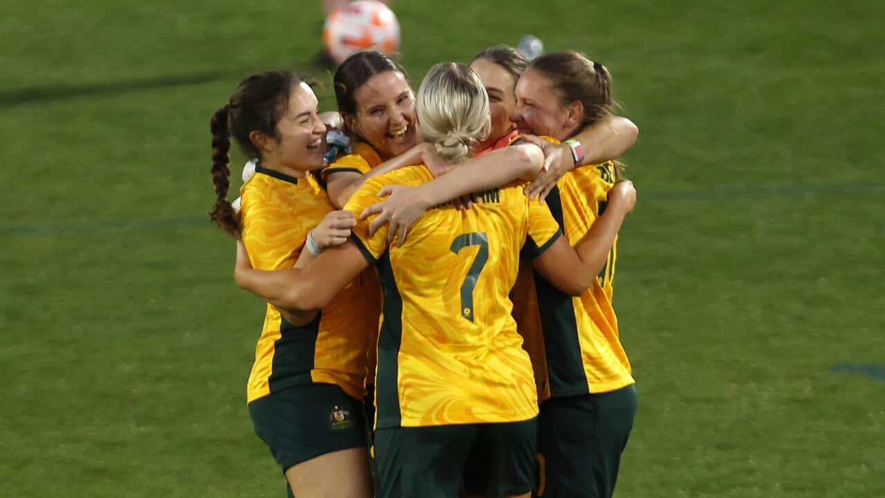 A group of female footballers hugging on the field.