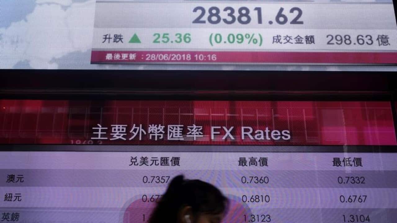 File image of a woman walking by a Hong Kong Stock Exchange screen.