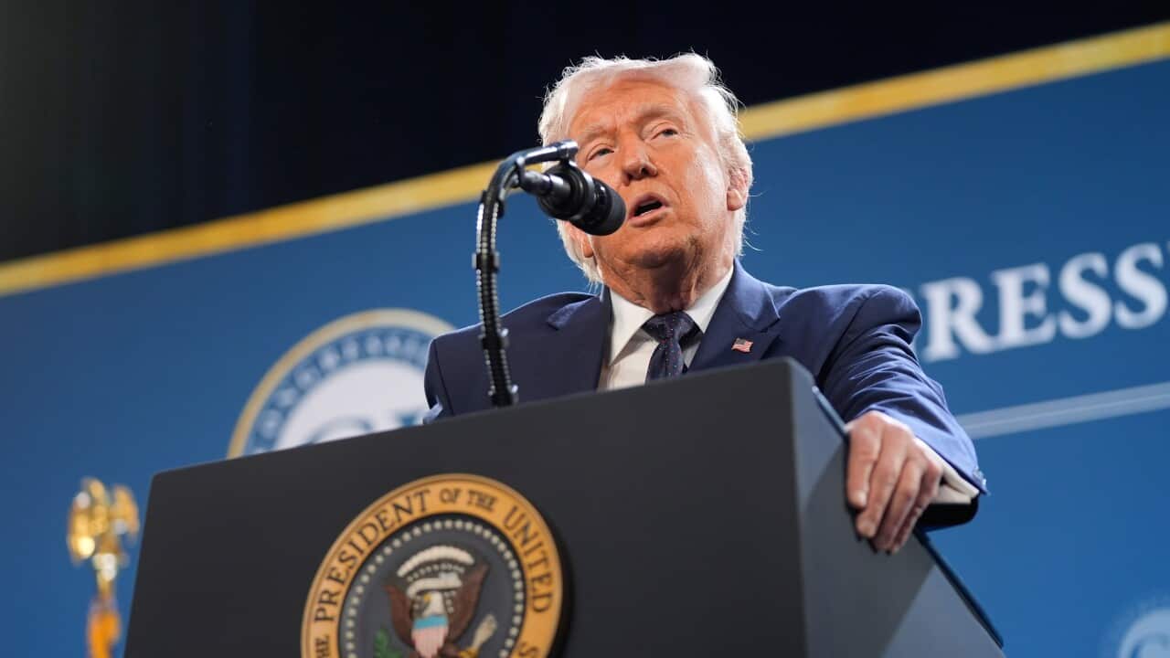 Donald Trump standing at a podium, speaking into a microphone.