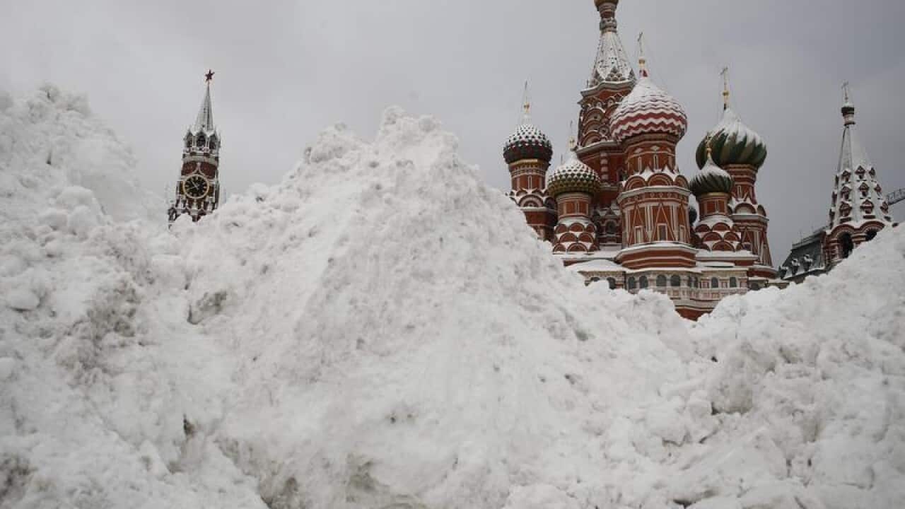 Snow covers Red Square with Spasskaya Tower and St. Basil's Cathedral.