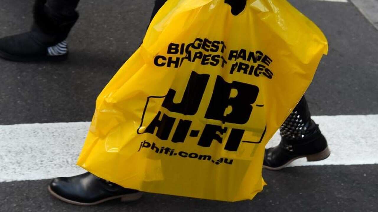 Person carries JB HI-FI bag on the street