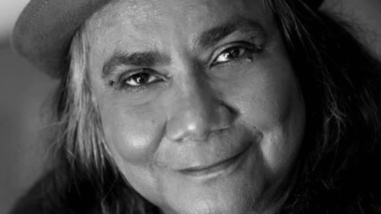 Image in black and white colours of Gayle Kennedy wearing a felt hat and beads.