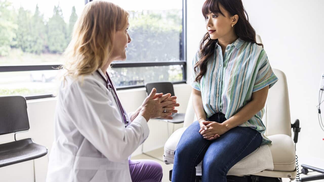 Female doctor talking with young woman in exam room