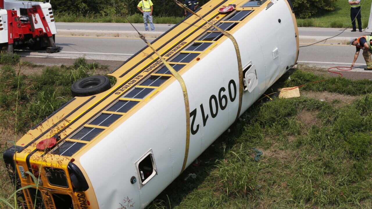 Workers right an overturned school bus in Kansas