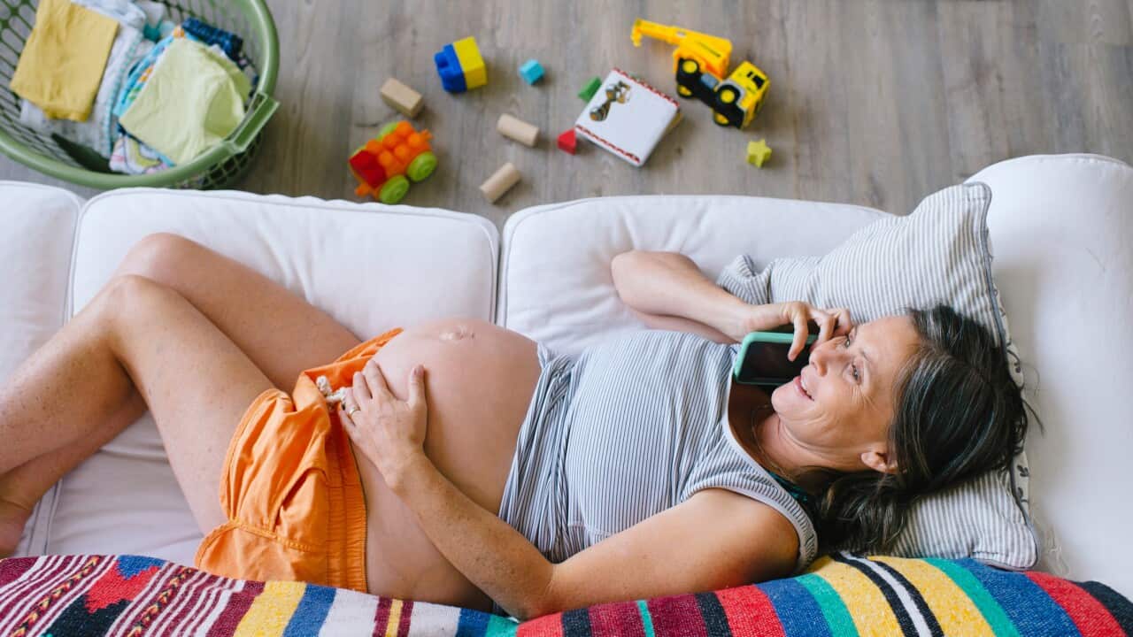 Portrait of mature pregnant woman using phone on sofa