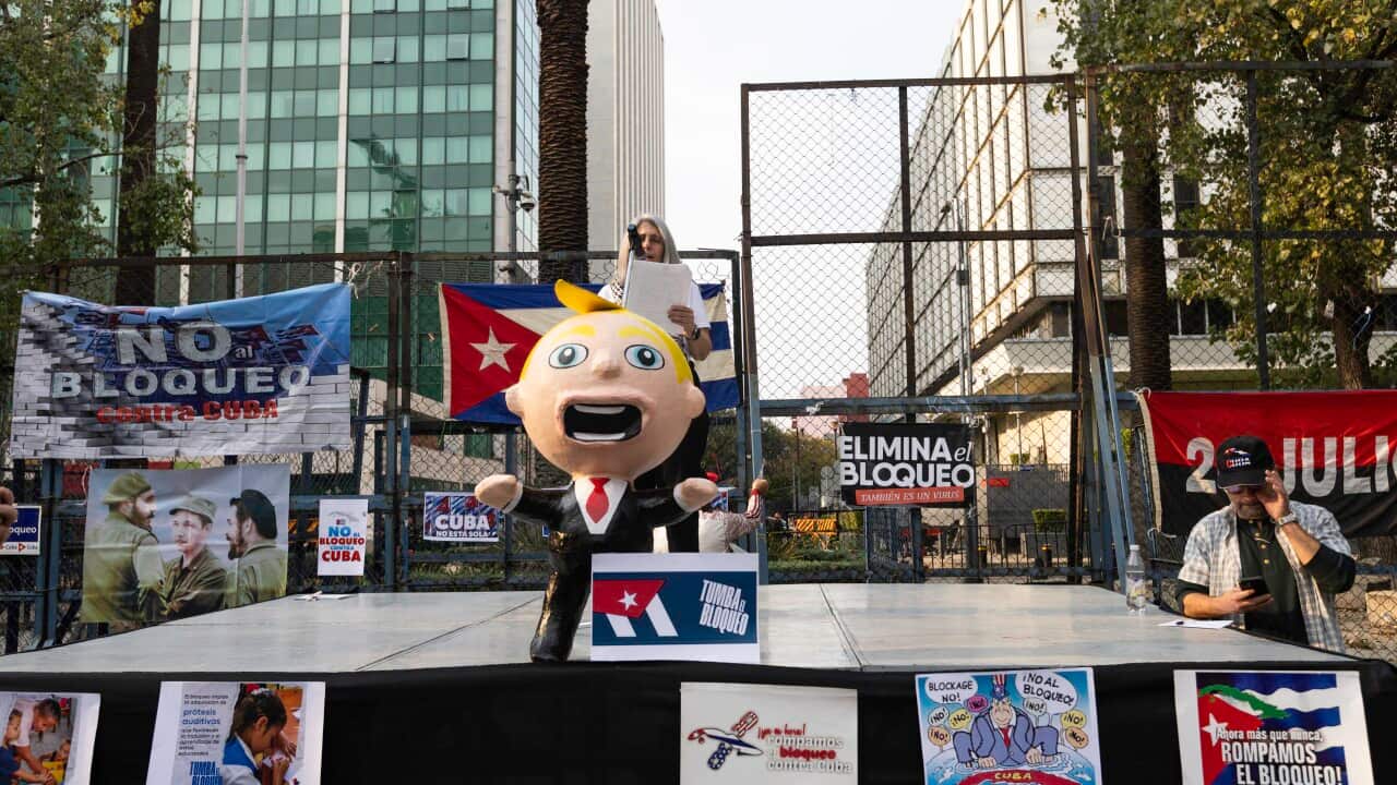 A blow-up doll of Donald Trump on a stage surrounded by signs denouncing the Trump administration's policies when it comes to Cuba
