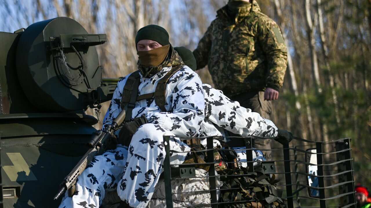 Ukrainian National Guard soldiers ride on top of a BTR-80 armored personnel carrier during an urban warfare exercise.