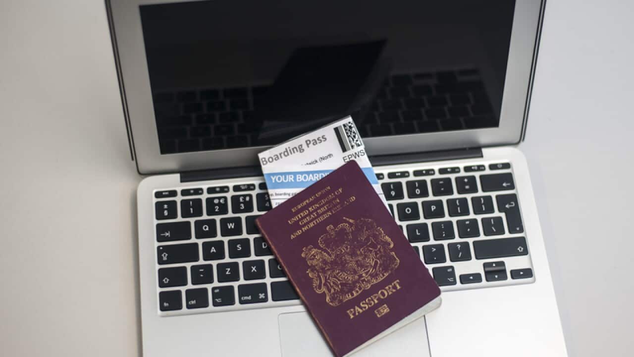 A passport containing airline boarding passes on top of a laptop