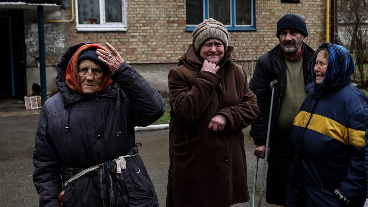 Women cry outside their houses in Bucha, northwest of Kyiv
