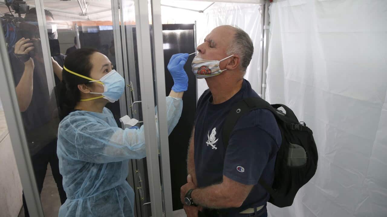 A medical technician collects a sample for a rapid coronavirus test at San Francisco Airport