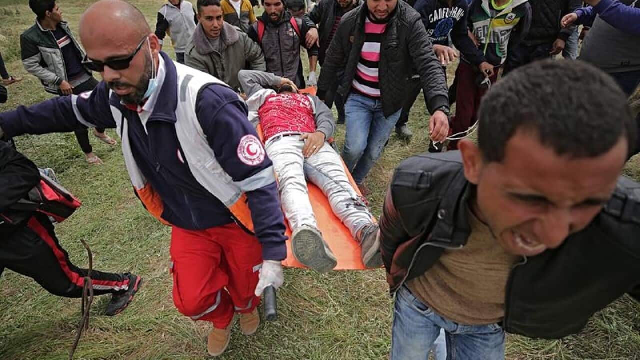 Palestinians carry a wounded youth shot by Israeli troops in Gaza