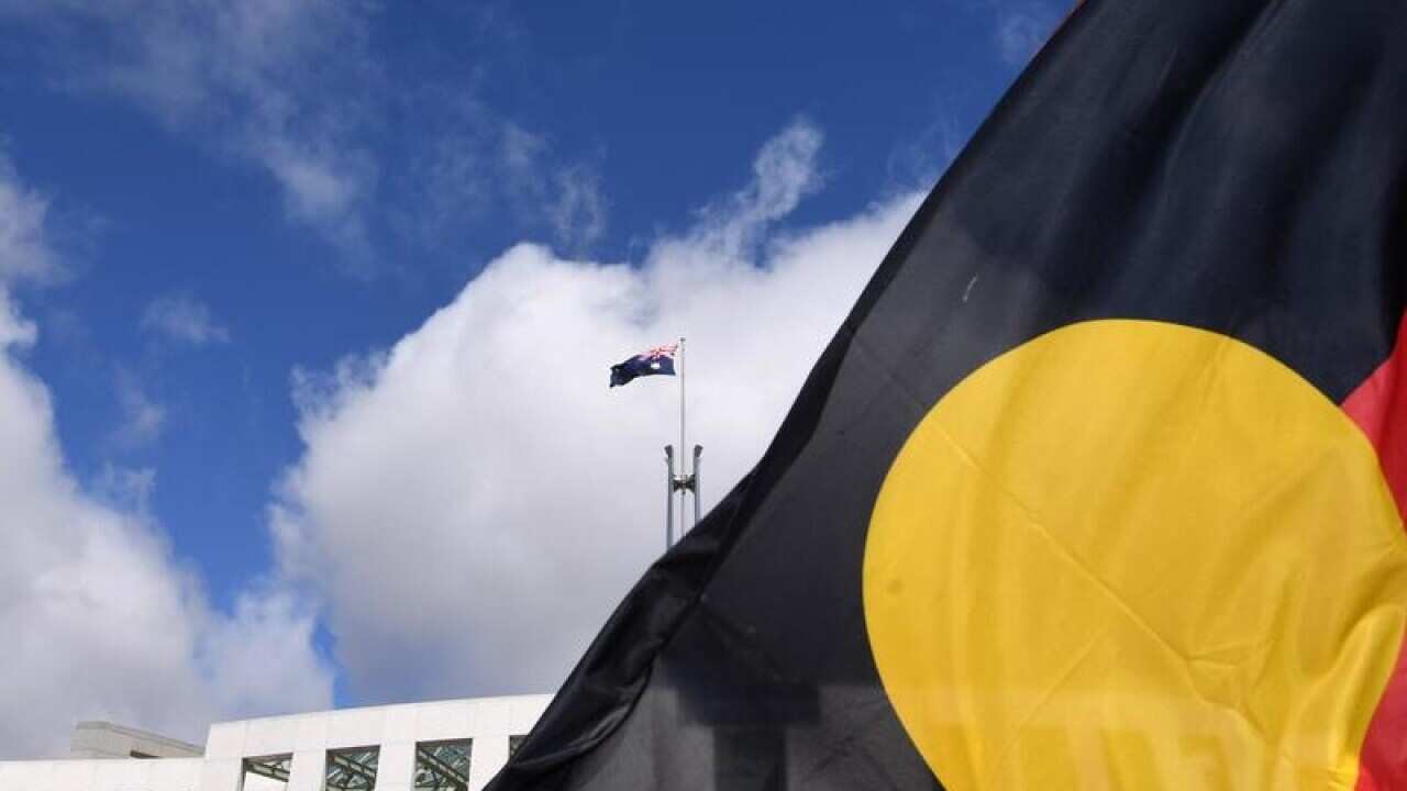 Australian Parliament House is seen through an Aboriginal flag