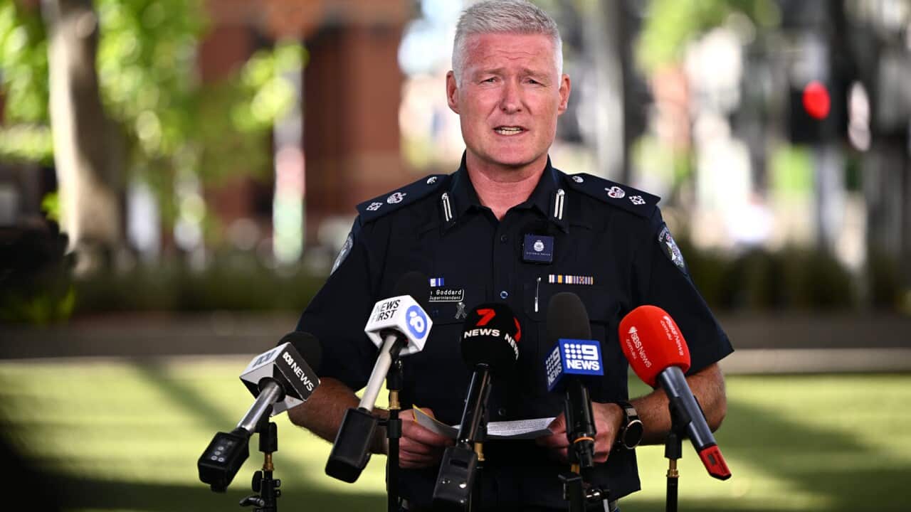 Victoria Police Inspector Jason Goddard stands in front of network microphones