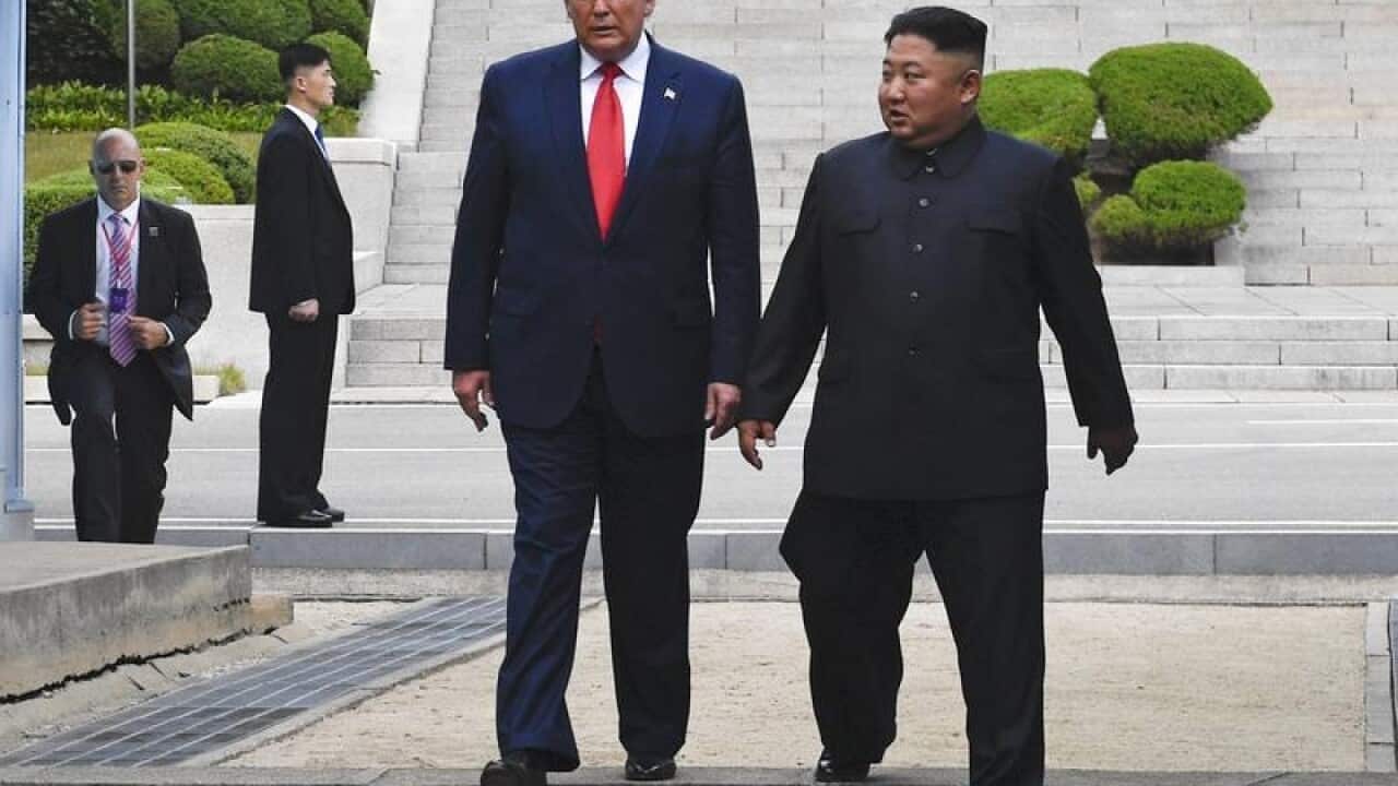 Donald Trump and Kim Jong Un step over the demarkation line.