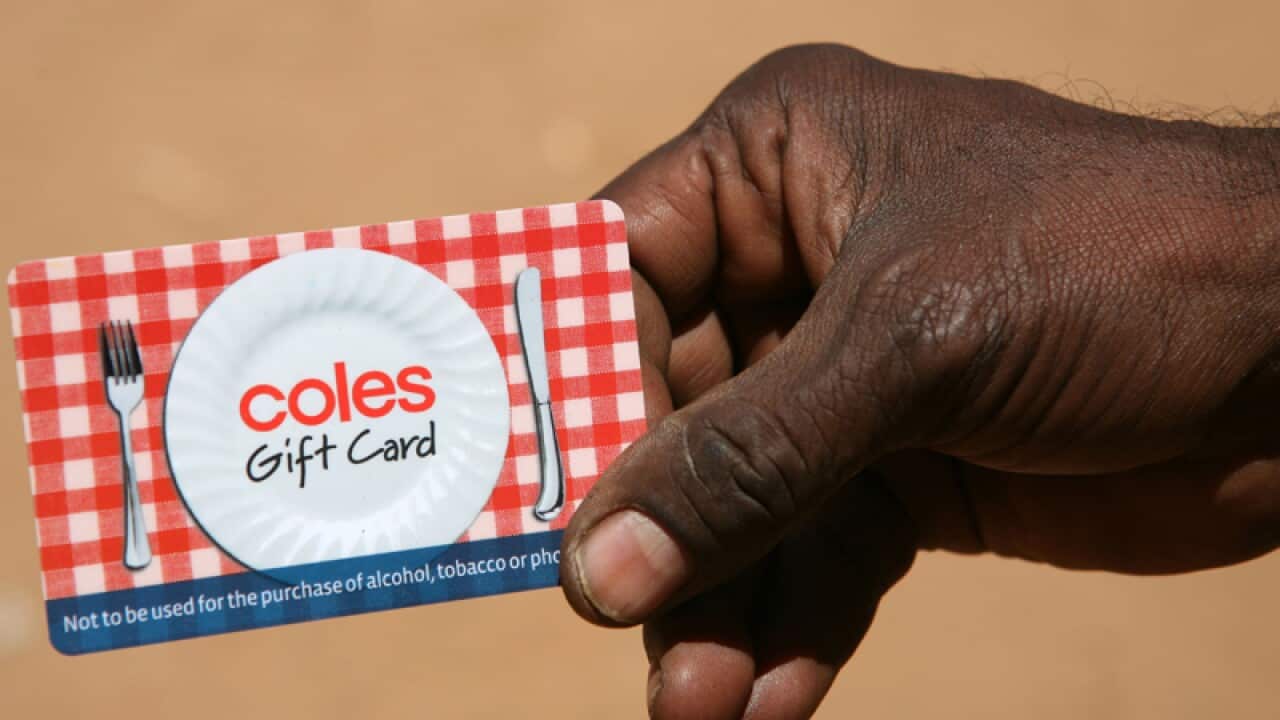 An indigenous man holds a gift card