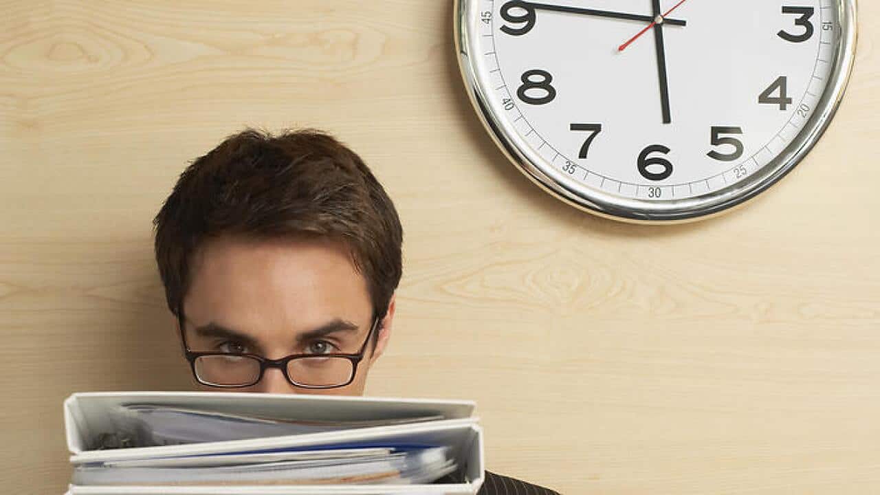 Businessman holding files standing under clock half length