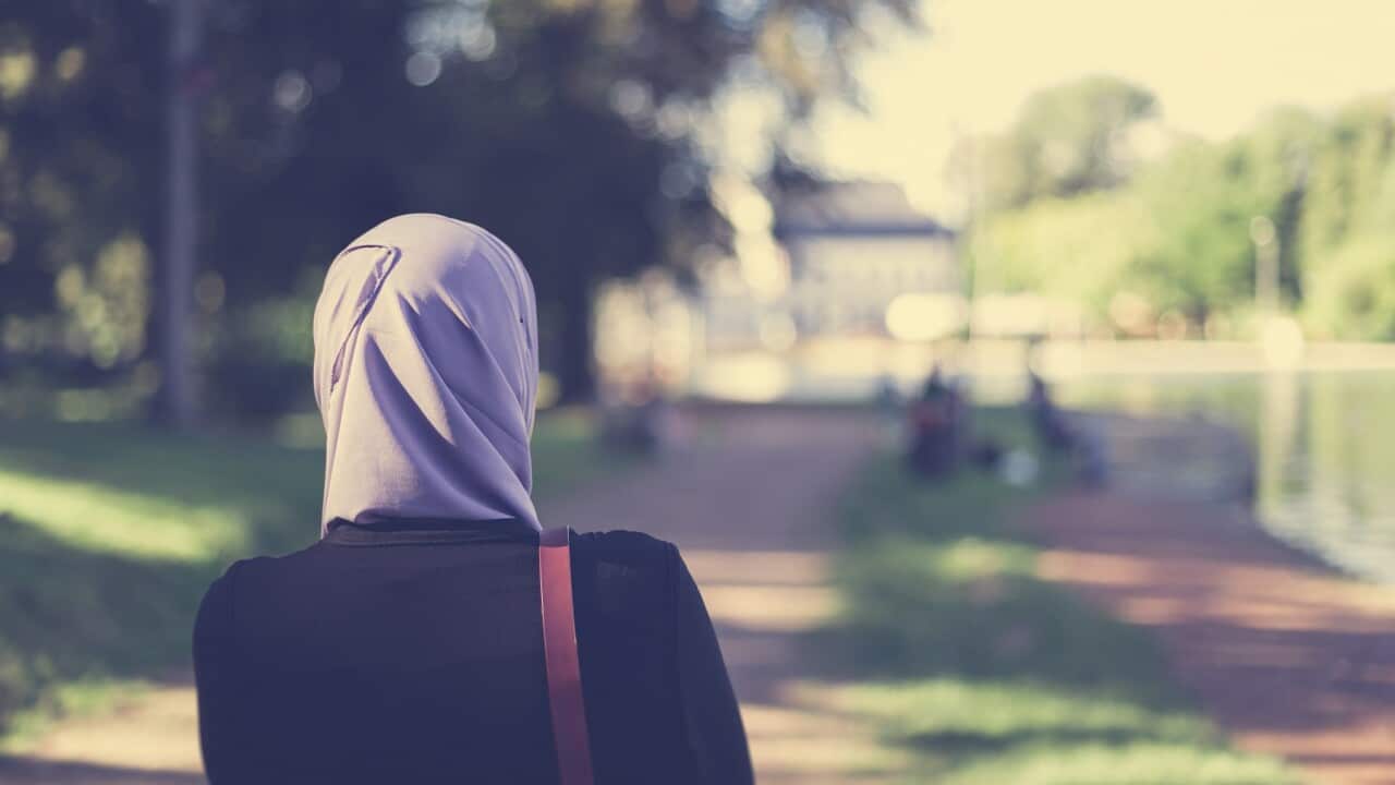 Rear view of a veiled muslim woman walking in forest