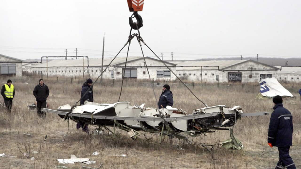 Workers remove parts of MH17 at the crash site