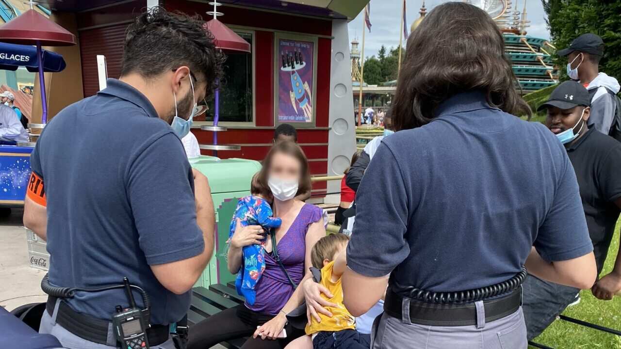 A supplied image shows Australian mum Laura (centre, blurred face), who now lives in Paris, being confronted by security guards for breastfeeding her two-month-old daughter at Disneyland Paris.