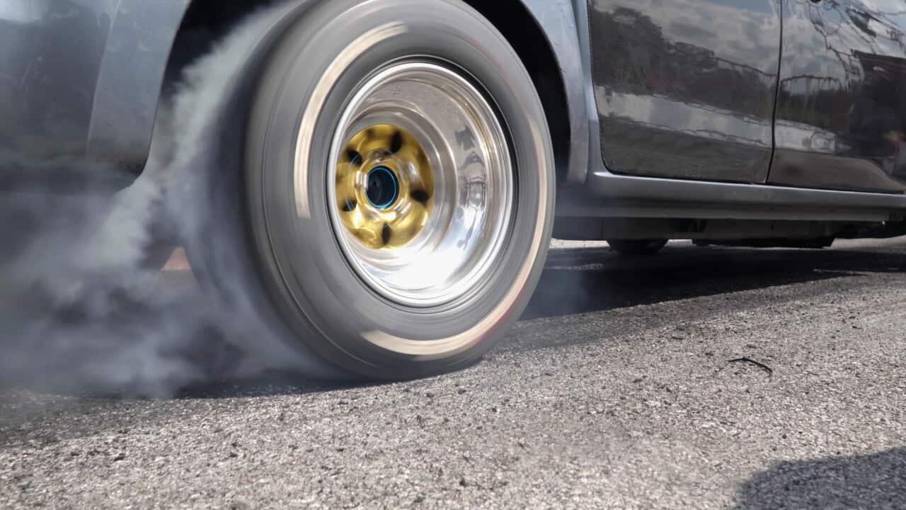 Drag racing car burning tire at starting line in race track