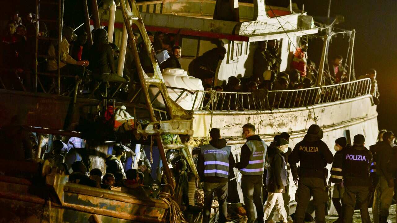 Police check a fishing boat with some 500 migrants in the southern Italian port of Crotone, early Saturday.
