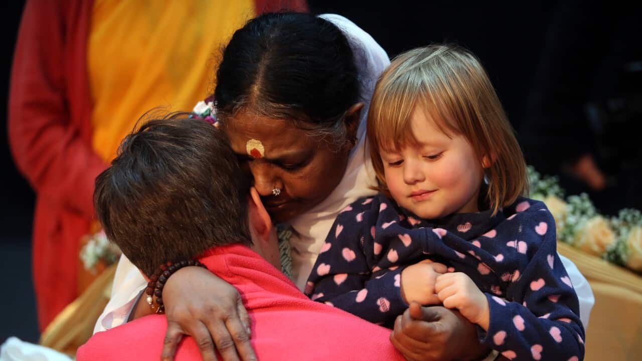 Mata Amritanandamayi Devi, primarily known simply as Amma ('Mother'), the hugging saint, hugs a devotee and two-year-old Elena in the event hall Arena, on November 12, 2014 in Berlin, Germany.