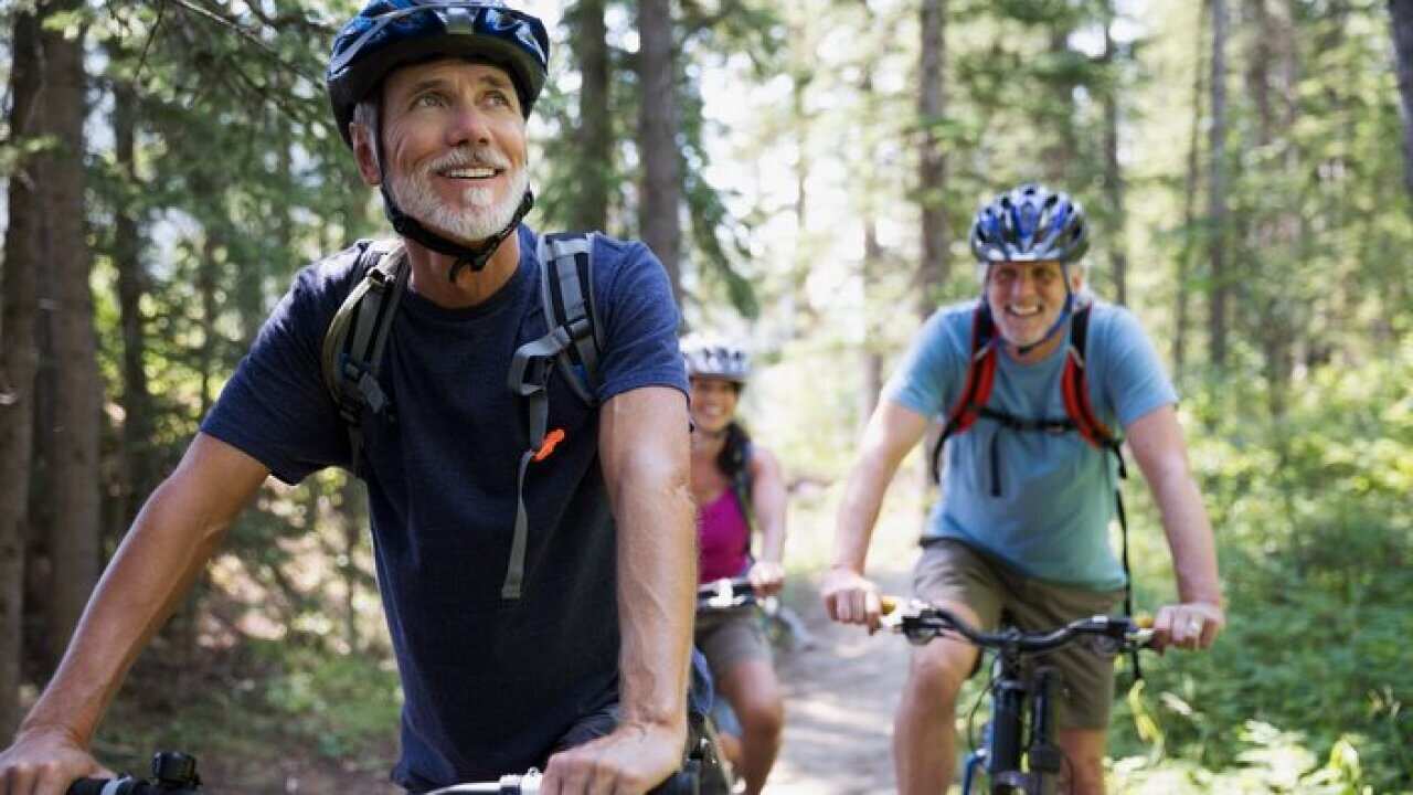 Smiling senior man mountain biking in woods