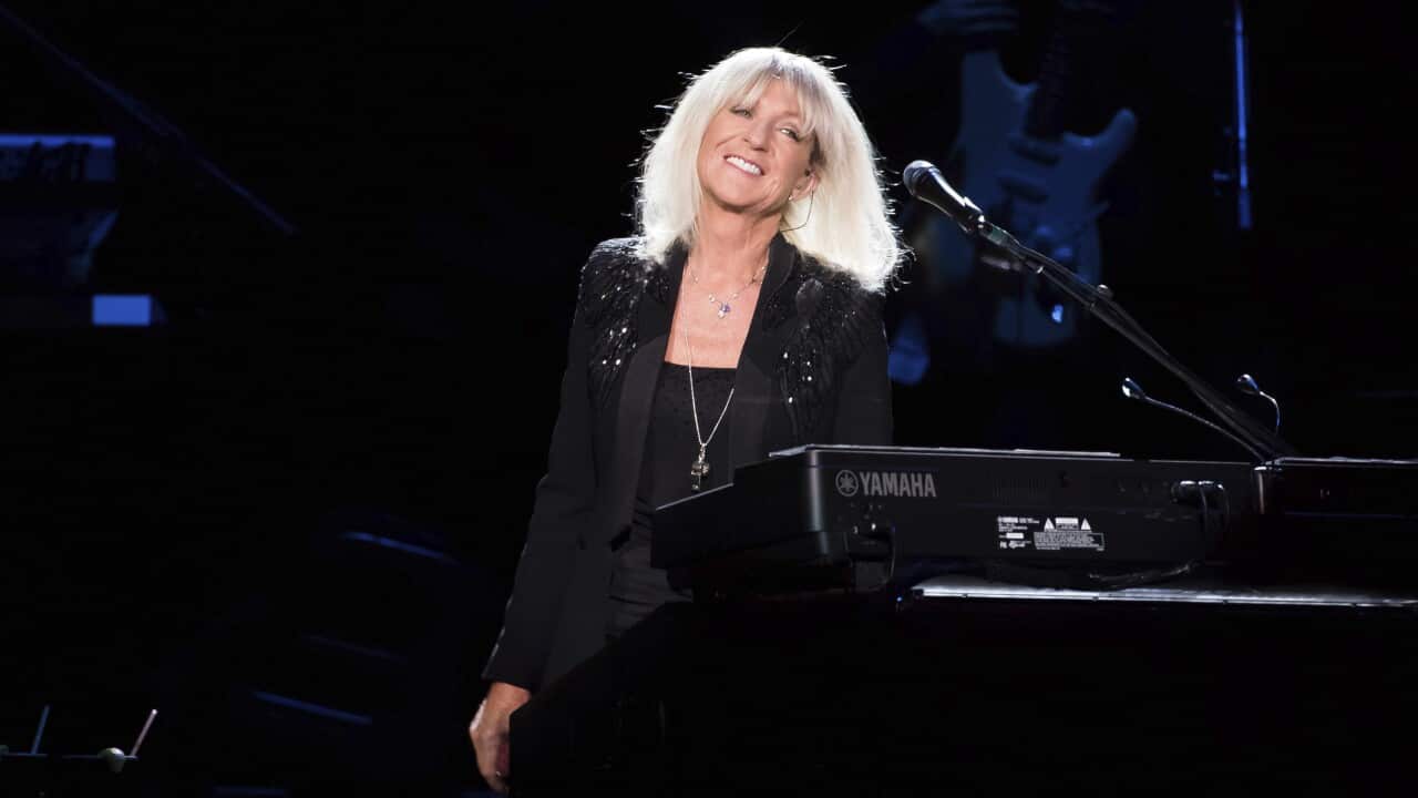 A woman standing in front of a keyboard smiling.