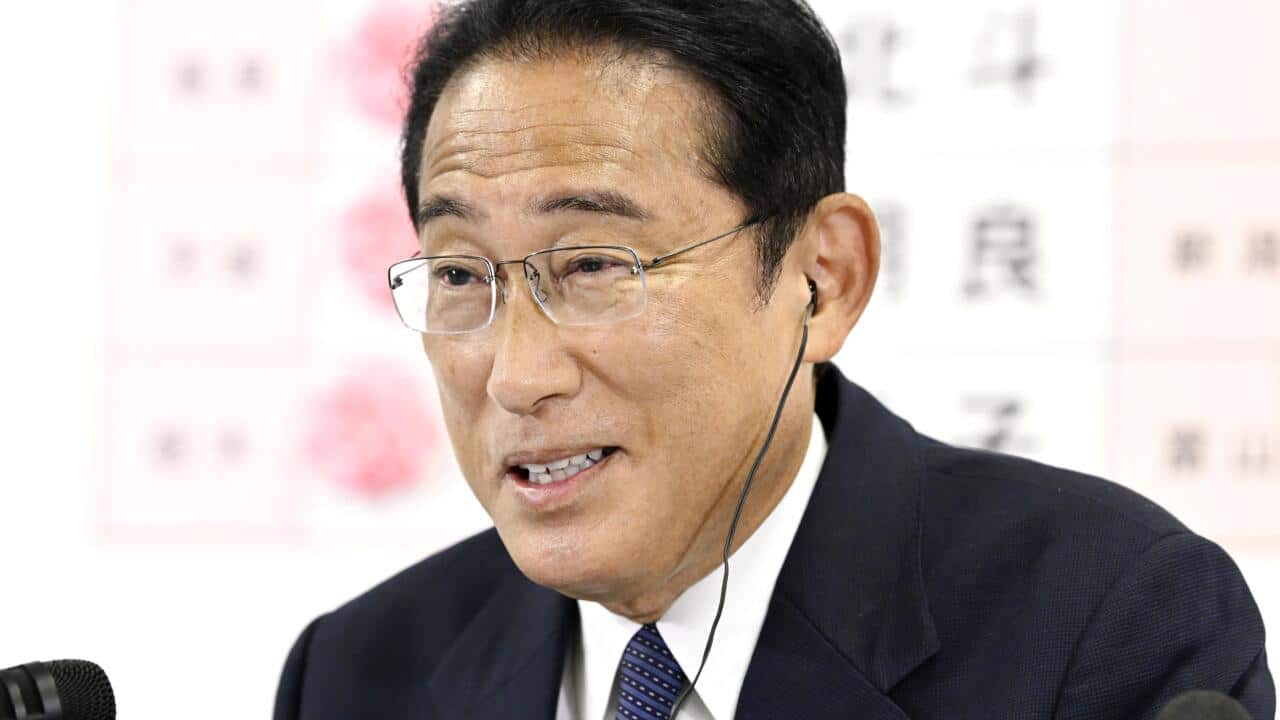 Fumio Kishida wearing an earpiece speaking into a microphone
