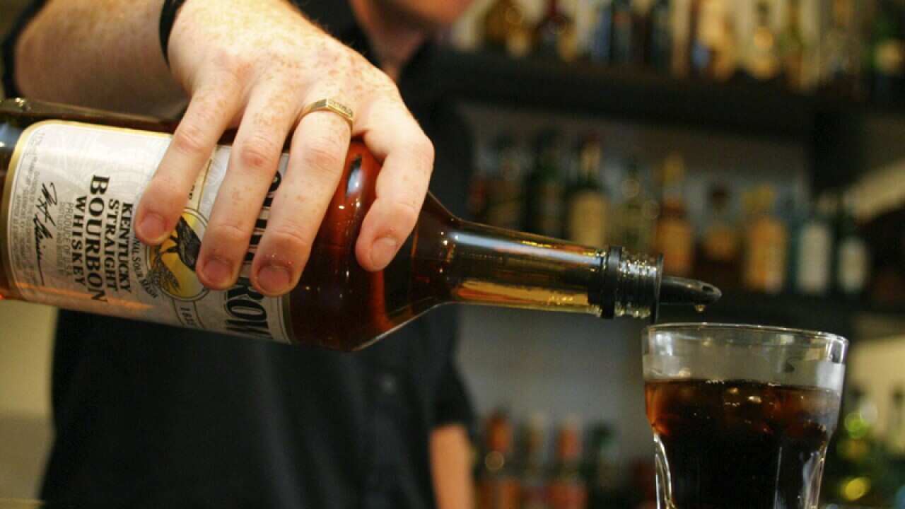 A barman pours a glass of bourbon